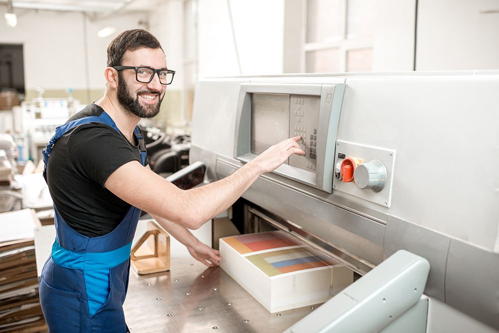 Man Working With Cutting Machine At The Printing Plant